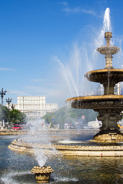 An ornate downtown fountain with the House of the People in the background